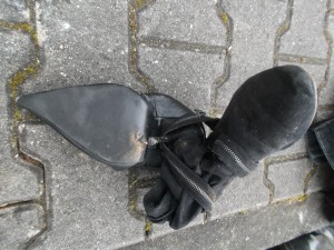 Seht genau hin: Der total zerquetschte Pumps hat sich beim Pressen durch die Schlaufe der Stiefelette durchgeschoben und dann mit dem abgestöckelten Absatz wieder in seine eigene Sohle gebohrt. Bösgeile Vernichtung!