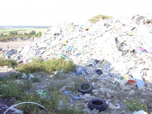 Oben links liegt ein gepresster (voller?) Koffer. Links sieht man die Stelle, wo Radlader den Hausmüll nach der Zwischenlagerung und nach Kapazität des Heizkraftwerks in große Container zur Müllverbrennungsanlage verfrachten.