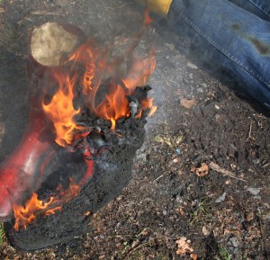 Nachdem die Flammen des Feuers dem rechten Gummistiefel schon arg zugesetzt haben ist der linke bereits bis auf die Sohle runtergebrannt.