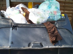 Eine vermutlich etwas kleinere Frau hat ihre ausrangierten Stiefel hoch oben auf den überquellenden Müllcontainer werfen müssen.