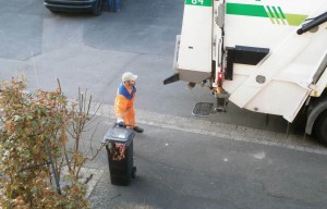 Müllwerker holt die Tonne. Die heraushängende Decke interessiert ihn nicht